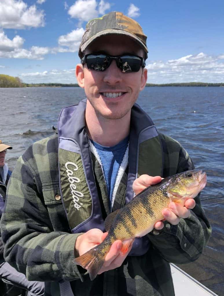 andrew juran holding a yellow perch on a boat