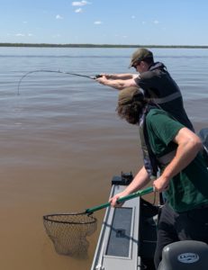 andrew juran and brother about to net fish with bent rod tip in dirty water