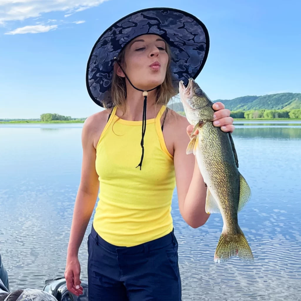 ornella juran holding walleye fish making a kissing face on the mississippi river