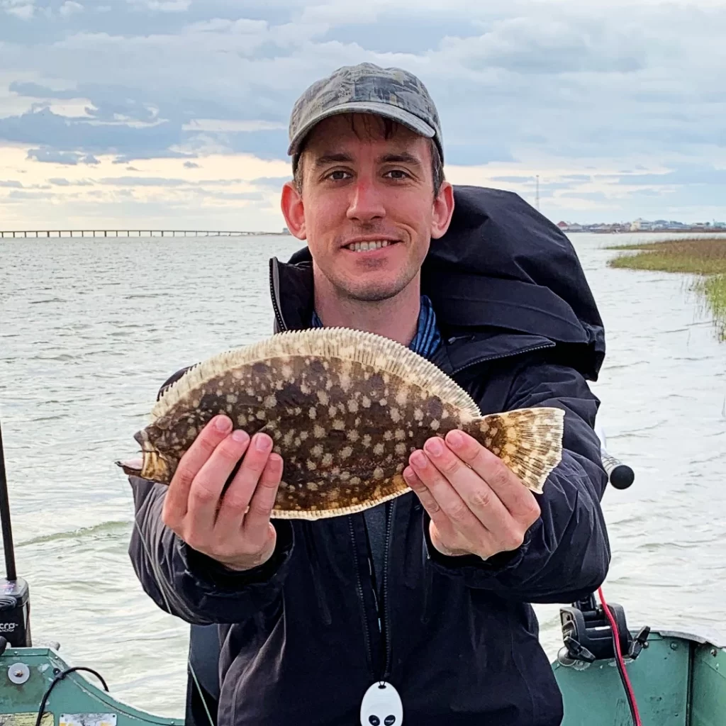 andrew juran holding small flounder caught inshore fishing with live bait on a circle hook