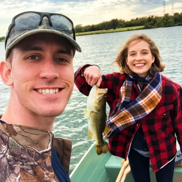 andrew juran and ornella juran bass fishing on a small boat holding a bass