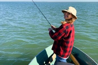 ornella juran fishing on a boat in red plaid jacket