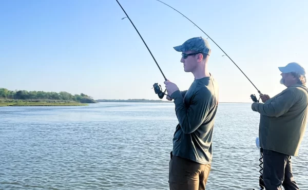 andrew juran on a boat reeling in a fish using a spinning fishing rod and reel