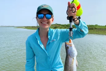 ornella juran wearing blue fishing shirt holding keeper size speckled trout in boga grip