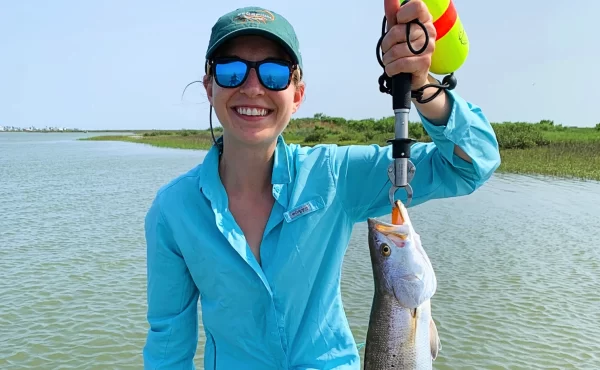 ornella juran wearing blue fishing shirt holding keeper size speckled trout in boga grip